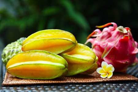 Different tropical fruit on wicker table outdoors, closeupの写真素材