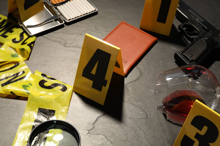 Forensic expertise. Crime scene with evidence, markers and police tape on gray background, closeup
