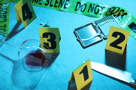 Forensic expertise. Crime scene with evidence, markers and police tape on blue background. Color toned effectの写真素材