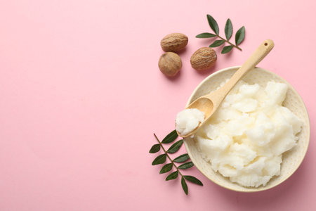 Natural shea butter, nuts and leaves on pink background, flat lay. Space for textの写真素材