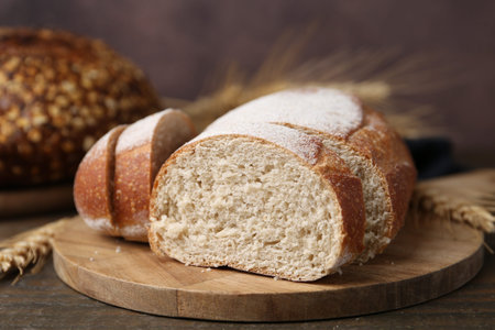 Fresh cut bread and spikes on wooden table, closeup