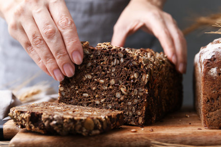 Woman with freshly baked bread at table against gray background, closeup