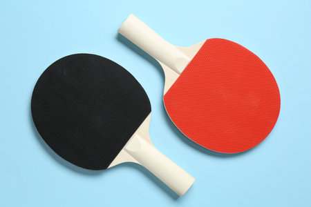 Ping pong rackets on light blue background, flat lay