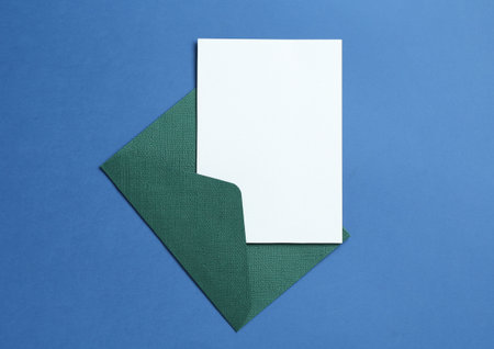 Blank invitation card and envelope on blue background, top view. Space for designの写真素材