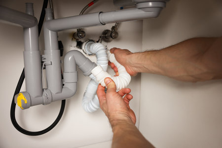 Plumber fixing pipes under sink indoors, closeupの写真素材