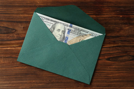 Money bonus. Envelope with dollar banknote on wooden table, top view