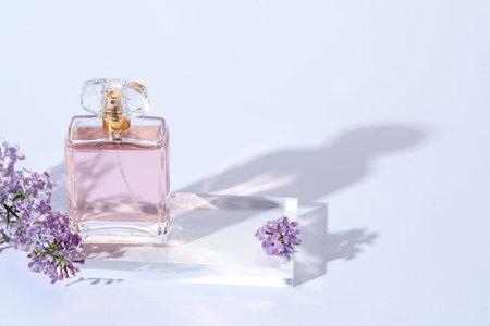 Bottle of perfume and lilac flowers on light gray background, closeup. Space for textの写真素材