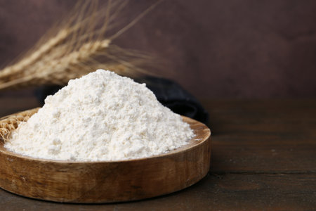 Wheat flour and spikes on wooden table, closeup. Space for textの写真素材