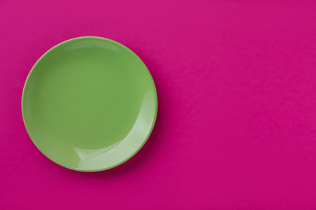 One empty plate on pink background, top view. Space for textの写真素材