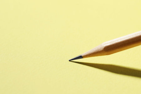 One graphite pencil on yellow background, closeup. Space for text