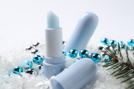 Moisturizing lip balms, Christmas decor and fir tree branches on artificial snow, closeup. Winter careの写真素材