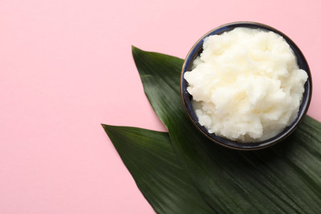 Natural shea butter and leaves on pink background, top view. Space for textの写真素材