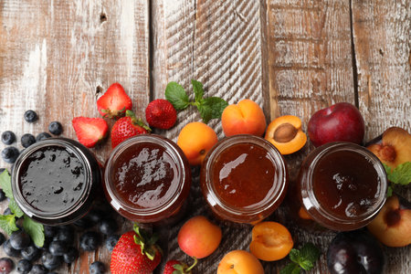 Different jams in jars and ingredients on wooden table, flat lay. Space for textの写真素材