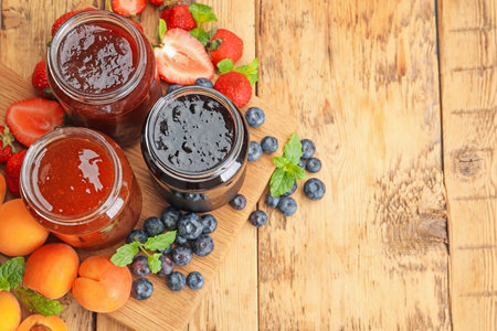 Different jams in jars and ingredients on wooden table, flat lay. Space for textの写真素材