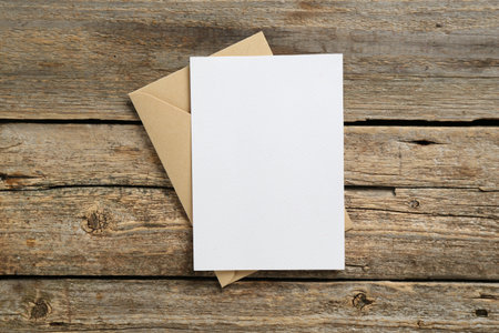 Blank invitation card and envelope on wooden table, top view. Space for designの写真素材
