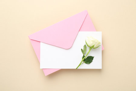 Blank invitation card, envelope and flower on beige background, top viewの写真素材