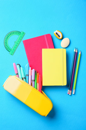 Pens and other stationery on light blue background, flat lay