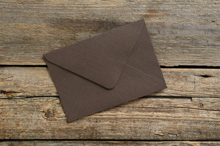 Beautiful invitation envelope on wooden table, top view