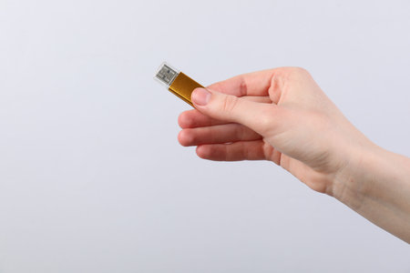 Man with modern flash drive on light gray background, closeup. Space for text
