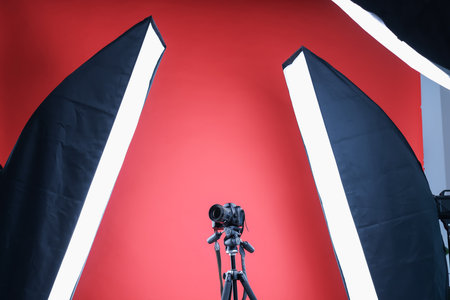 Modern video camera and professional lighting equipment on red background, low angle viewの写真素材