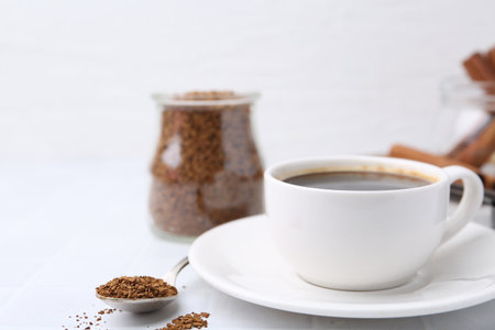 Cup of aromatic coffee and granulated instant coffee on white table, closeup. Space for textの写真素材