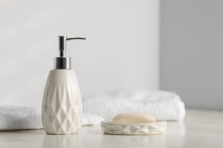 Soap bar, bottle of cosmetic product and towels on white table