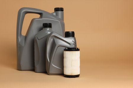 Motor oil in plastic canisters and filter on beige background, space for textの写真素材