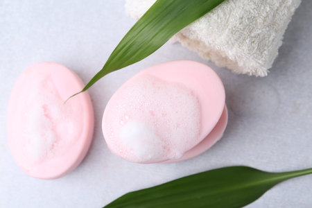 Soap bars with foam on white table, flat lay