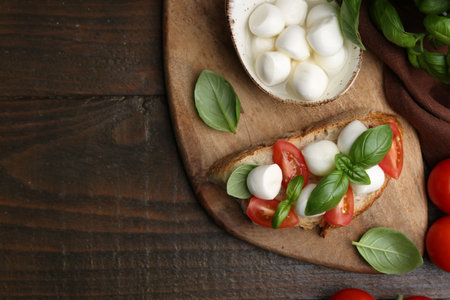 Tasty sandwich with mozzarella cheese, tomatoes and basil on wooden table, flat lay. Space for textの写真素材