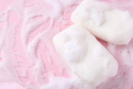 Soap bars with foam on pink background, closeup. Space for textの写真素材