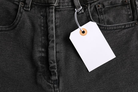 Cardboard tag on black jeans, top view