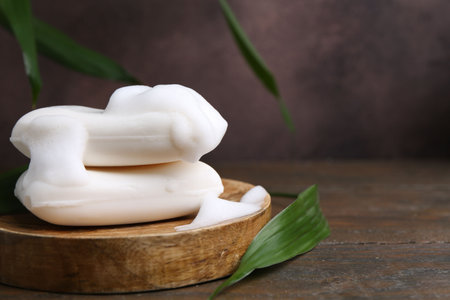 Soap bars with foam on wooden table, closeup. Space for textの写真素材