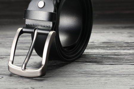 One black leather belt on wooden table, closeup. Space for textの写真素材