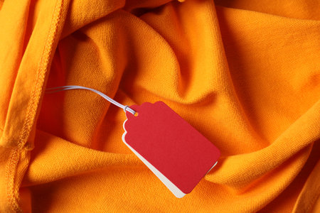 Cardboard tags on orange garment, top viewの写真素材
