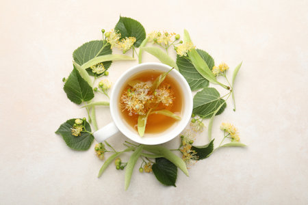 Fresh linden tea in cup and flowers on white table, flat layの写真素材