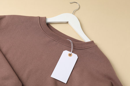 Brown garment with tag on beige background, top viewの写真素材