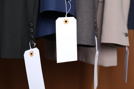 Different jackets with tags on brown background, closeupの写真素材