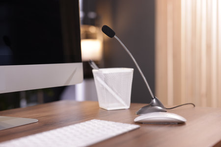 Microphone and computer on wooden desk indoorsの写真素材