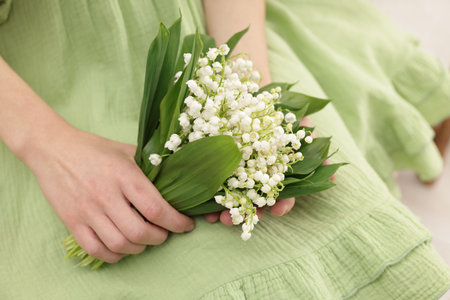 Woman with beautiful lilies of the valley flowers indoors, closeupのeditorial素材