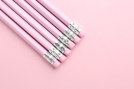 Graphite pencils with erasers on pink background, flat lay. Space for textの写真素材