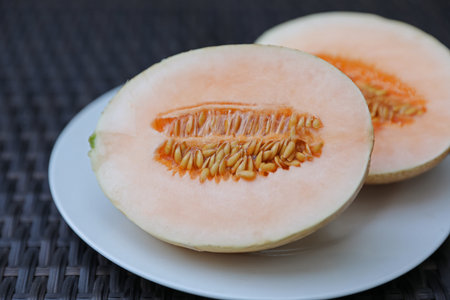 Halves of juicy melon on wicker table, closeupの写真素材