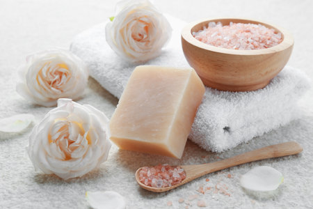 Soap bar, sea salt, flowers and towel on white textured table, closeupの写真素材