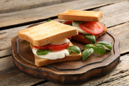 Tasty sandwiches with mozzarella cheese, tomatoes and basil on wooden table, closeupの写真素材