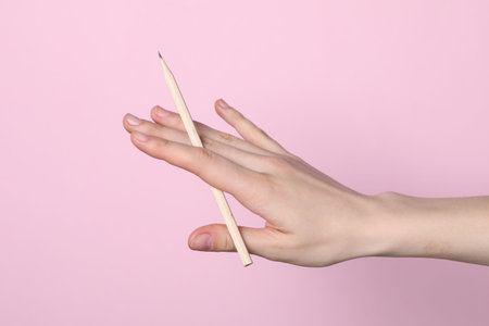 Woman with graphite pencil on pink background, closeupの写真素材