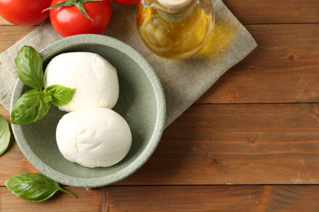 Tasty mozzarella balls, tomatoes, oil and basil on wooden table, flat lay. Space for textの写真素材