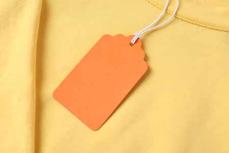 Cardboard tag on yellow garment, top viewの写真素材