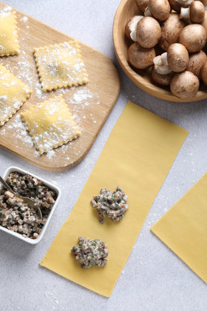 Making ravioli with mushrooms at light table, flat layの写真素材