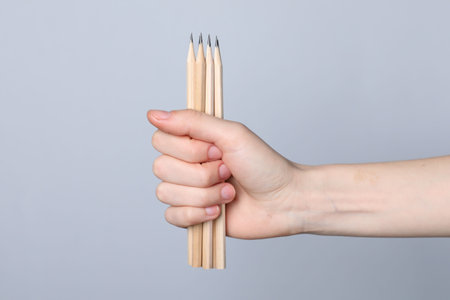 Woman with graphite pencils on grey background, closeupの写真素材
