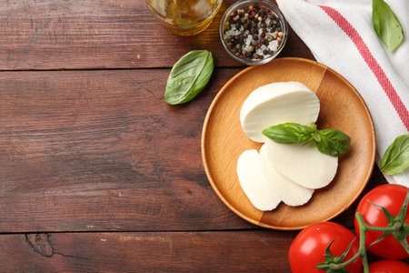 Tasty mozzarella, tomatoes and basil on wooden table, flat lay. Space for textの写真素材