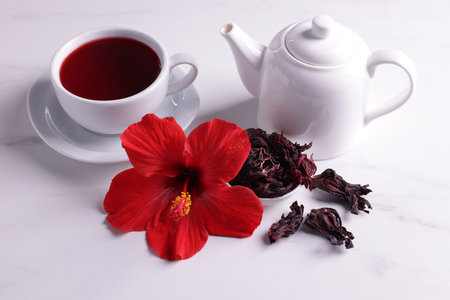 Tasty hibiscus tea, dry roselle sepals and beautiful flower on white tableの写真素材